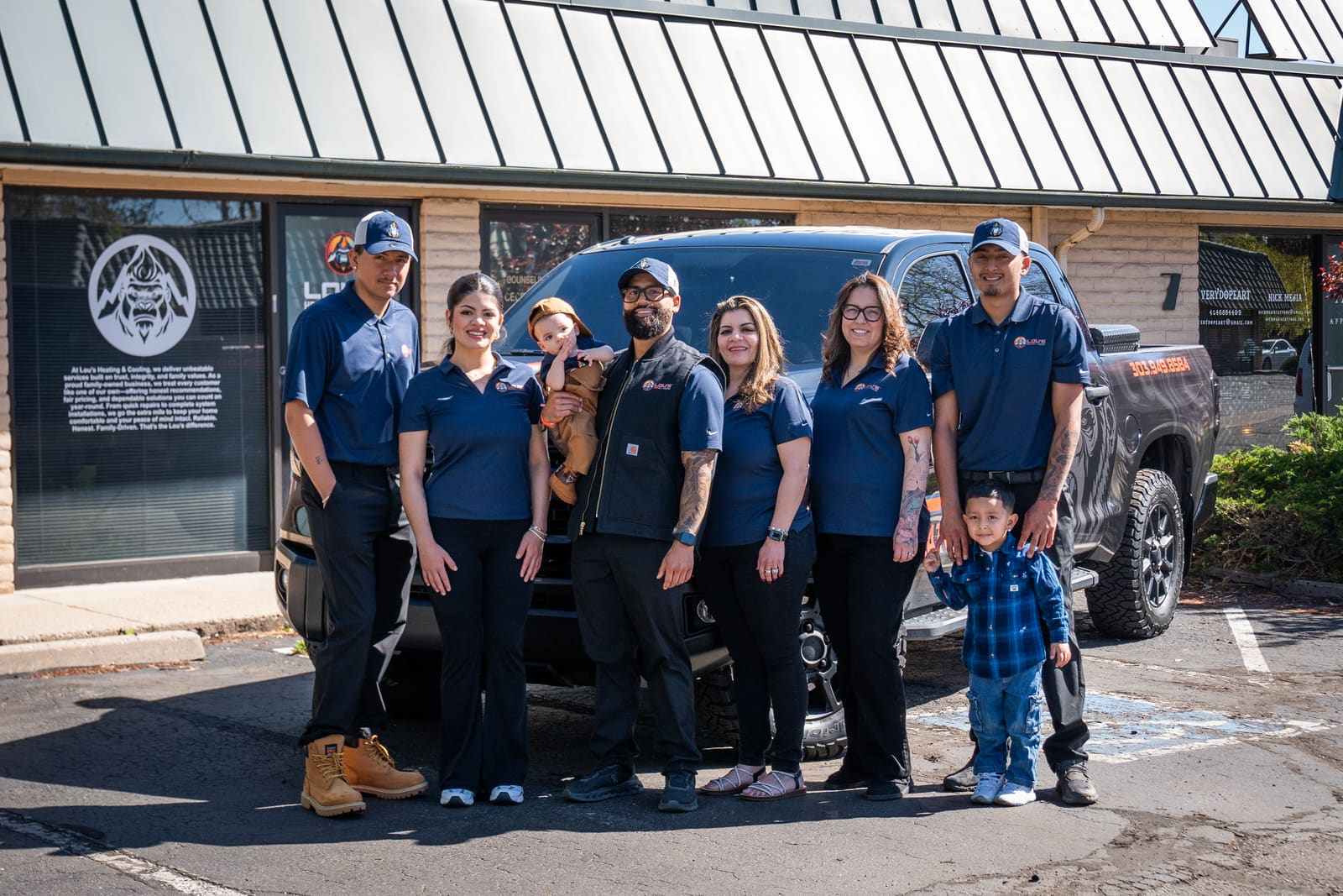 Lou Hernandez and the Lou's Heating & Cooling family team standing in front of their branded service truck in Lakewood, Colorado
